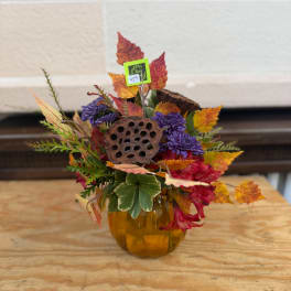 Fall floral arrangement in an amber glass vase with purple and red blooms