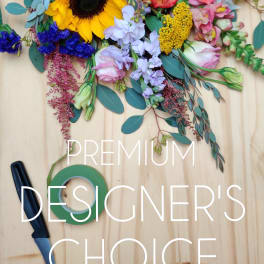 Mixed bouquet with sunflower, roses, and pastel blooms on a wooden surface
