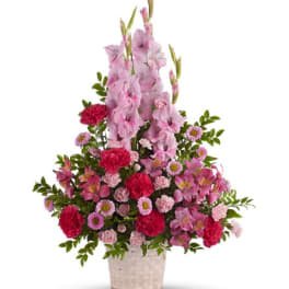 Pink and red floral arrangement in a woven basket