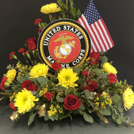 Floral tribute with red roses, yellow mums, and a U.S. Marine Corps emblem