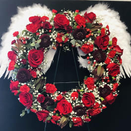 Heart-shaped floral wreath with red roses and white feathers