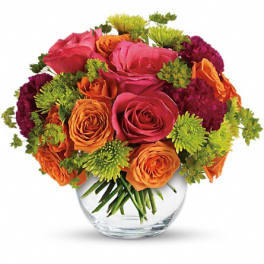 Mixed bouquet of pink, orange, and green flowers in a glass vase