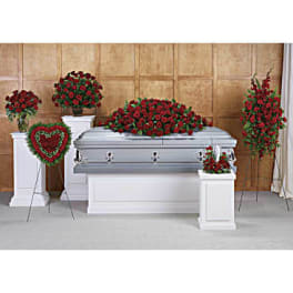 Sympathy set of red rose arrangements around a silver casket, including sprays and a heart wreath