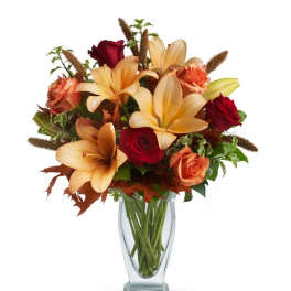 Bouquet of peach lilies and red roses in a clear glass vase