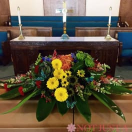 Large floral arrangement with yellow daisies and orange roses in front of a church altar