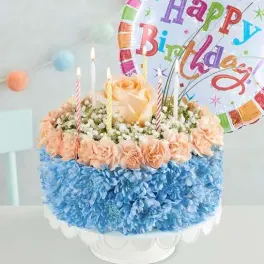 Birthday cake with blue and peach flowers and candles, topped with a Happy Birthday balloon