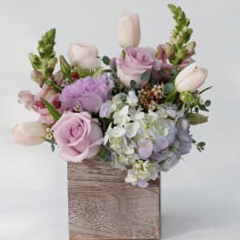 Pastel bouquet of roses, tulips, hydrangea, and snapdragons in a wooden box