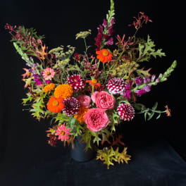 Colorful mixed bouquet in a dark vase with pink, orange, and burgundy blooms