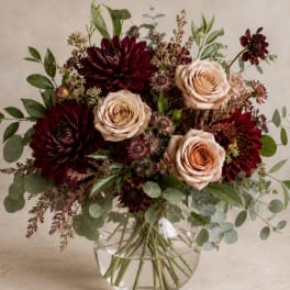 Bouquet of burgundy dahlias and blush roses in a clear glass vase
