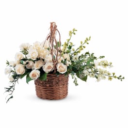 Cream roses and carnations in a wicker basket with trailing greenery