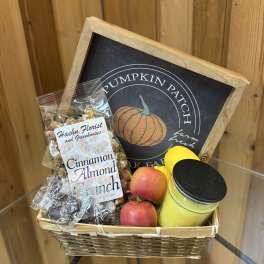 Basket of apples, candy, and a candle with a pumpkin patch sign