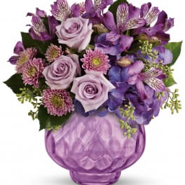 Purple bouquet of roses, alstroemeria, and mums in a lavender glass vase