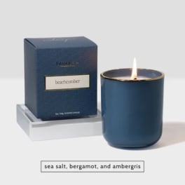 Blue scented candle in a glass jar beside its box