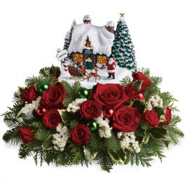 Red rose arrangement with a snowy Christmas village centerpiece