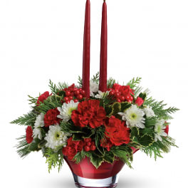 Red and white floral centerpiece with two tall red candles in a glass vase