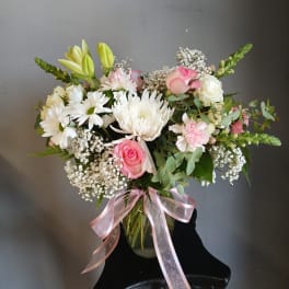 Pink and white mixed bouquet in a glass vase with a pink ribbon