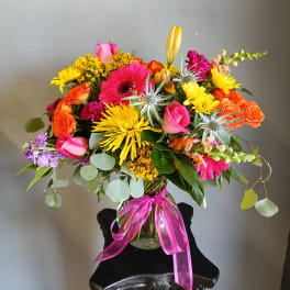 Colorful mixed bouquet in a glass vase with a pink ribbon