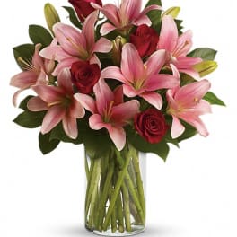 Bouquet of pink lilies and red roses in a clear glass vase