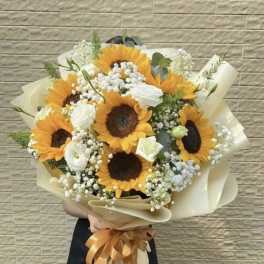 Bouquet of sunflowers and white blooms wrapped in cream paper