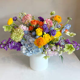 Colorful mixed bouquet in a white vase with roses and hydrangeas