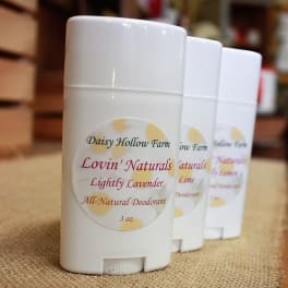 Three white deodorant sticks with lavender labels on a burlap surface