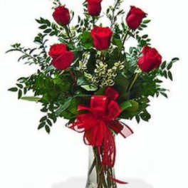 Red roses arranged in a clear glass vase with a red ribbon