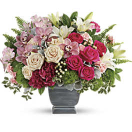 Mixed bouquet of pink roses, lilies, and orchids in a gray vase
