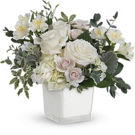 White and blush floral arrangement in a clear square vase