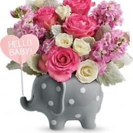 Pink and white roses in a gray elephant planter with a "Hello Baby!" sign