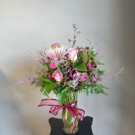 Pink and purple mixed bouquet in a glass vase with a ribbon