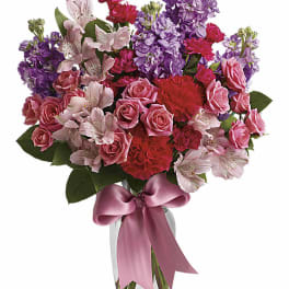 Pink and purple mixed bouquet in a glass vase with a pink ribbon