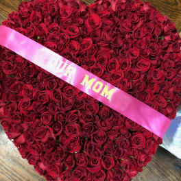 Heart-shaped bouquet of red roses with a pink ribbon