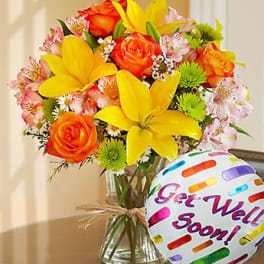 Vase of yellow lilies, orange roses, and pink blooms with a colorful 'Get Well Soon!' balloon.