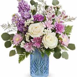 Purple and white mixed bouquet in a blue glass vase
