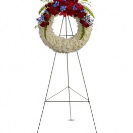 Standing floral wreath with red, white, and blue flowers on an easel