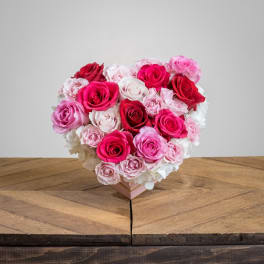 Heart-shaped bouquet of pink, red, and white roses in a box