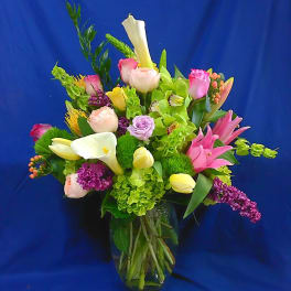 Mixed bouquet with pink roses, calla lilies, and purple flowers in a glass vase