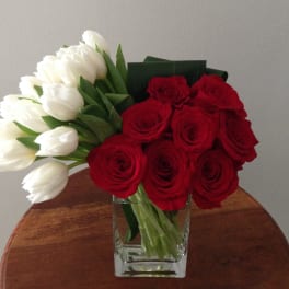 Red roses and white tulips in a clear glass vase