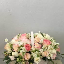 Basket of pink and white roses with small white flowers