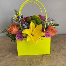 Bright mixed flower arrangement in a neon yellow gift bag