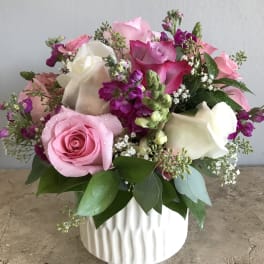 Pink and white roses arranged in a white vase.