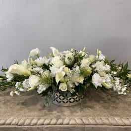 Low white floral arrangement in a decorative silver bowl