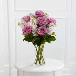 Pink roses in a clear glass vase with small white filler flowers