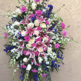 Large standing spray of pink lilies, white roses, and blue flowers