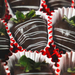 Box of chocolate-covered strawberries in red and white paper cups