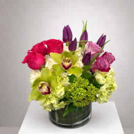 Pink roses and green orchids arranged in a glass vase
