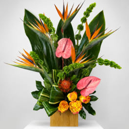 Tropical floral arrangement with pink anthuriums and bird of paradise in a wooden vase