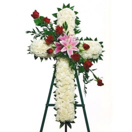 Floral cross on an easel with white blooms, red roses, and pink lilies