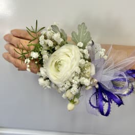 White ranunculus corsage with baby's breath and purple ribbon