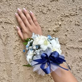 White floral wrist corsage with blue ribbon and tulle